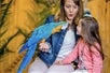 A mother and her daughter are having fun with a Blue and Yellow Macaw parrot.
