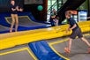 Children playing on trampolines, while throwing a ball to another.