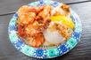 A paper plate of heavily seasoned shrimp with rice and fruit from Shrimp Trucks.