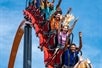 Several people raise their hands in excitement while going down aboard the Jersey Devil roller coaster on a sunny day.