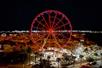 Aerial view of the SkyWheel in Panama City Beach at night with the lights on the wheel glowing red.