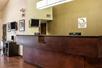 A dark brown front desk with a smaller business desk next to it and an olive green wall behind it with a Sleep Inn sign.