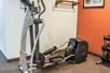 An elliptical machines next to a weight bench and a red accent wall with art on the walls around it.