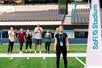 A woman trying to do a high jump while friends are cheering at the background at SoFi Stadium