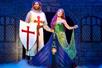 A woman in a green dress and a knight with a shield standing in a boat with fog around them in the musical Spamalot.