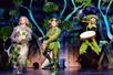 A group of musicians wearing bright green costumes dancing and playing their instruments on stage in the musical Spamalot.