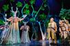 The cast of Spamalot performing on stage with dimly lit fake trees in the background in New York City, New York.