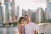 A man and woman smiling while posing for a photo on the deck of a cruise boat on a sunny day with the city of Chicago behind them.