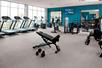 A fitness center with several treadmills and other cardio equipment, a large weights sections, several mirrors, and a wall of windows.