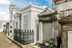 Several white stone tombs belonging to different families lined up next to each other at St. Louis Cemetery No. 1.