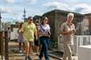 Tourists following their guide on a walking tour of St. Louis Cemetery No. 1 with tombs all around them.