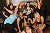 A group of several women laughing and having fun while posing for a group photo at the Stripper 101 - Pole Dancing Class.