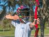 A man displays a red bow and arrow while wearing a helmet and safety glasses