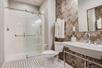 Shower with glass door, fresh towels, toilet and a spacious sink inside a private bathroom.