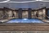An indoor hot tub with gray stone around it and stairs leading up on both sides at the Sahra Spa Salon & Hammam.