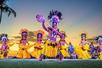 Hula dancers performing in yellow skirts and headdresses on the beach at sunset at The Feast at Mokapu Luau in Wailea, Hawaii, USA.