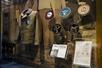 A display of old military uniforms and several different styles of patches with on hand written documents at the bottom of the display.