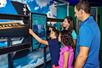 A family of four interacting with a touch screen exhibit at the The Intrepid Sea, Air & Space Museum.