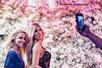 A woman posing for a photo with a was figure of Khloe Kardashian with a wall of roses behind them at Madame Tussauds in Las Vegas.