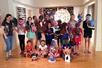 A group of children posed together holding up masks they have made at the Coral Springs Museum of Art.