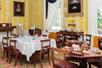 A historic dining room with yellow walls and old tables set for dinner at Travellers Rest Historic House Museum.