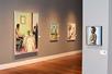 Several paintings displayed on light gray walls at the Ogden Museum of Southern Art.