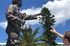 A man reaching up to touch a statue that has its hand out with a blue sky behind them on the Scavenger Hunts - Orlando.