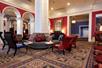 A lounge area with ornate carpet, red and white walls, and red and black furniture in the lobby of the The Royal Sonesta Portland Downtown.