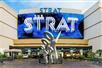 The exterior blue, black, and white sign for the The STRAT Hotel, Casino & SkyPod and a silver statue in Las Vegas, Nevada.