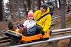 A young girl and her father having a good time while going down hill on the Rocky Top Mountain Coaster.