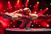 Two shirtless mes in red leather pants doing an acrobatic performance on stage with red lights at V - The Ultimate Variety Show.
