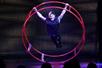 A man in all black performing acrobatics on a red metal wheel at V - The Ultimate Variety Show in Las Vegas, NV.