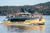 The pale yellow Salish Sea Eclipse Catamaran with its decks full of tourists on a sunny day.