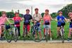 A group of tourist wearing red helmets and smiling white holding their bikes up with the Washington Monument in the background.
