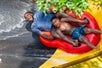 A father and son tightly grip the handles as they ride in a red inflatable tube, plunging down from Dragon's Den at Water Country in Portsmouth, New Hampshire.
