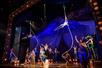 The cast of Water For Elephants during a circus scene with people in circus costumes and two actors on arial silks.