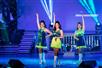 Three girls wear blue and green costumes during the show