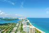 Aerial view looking down on North Beach Miami on a bright and sunny day with the city on the left and deep blue ocean on the right.