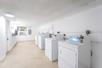 A laundry room with several white machines along the right wall at the PRAIA Hotel, Boutique & Apartments.