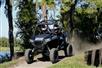 Two guests come up a small hill on a trail in their all terrain vehicle
