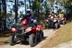 Three guests wear safety helmets while riding red ATVs