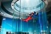 An instructor and a guest with their arms out flying high in the air in the skydiving tunnel at iFly.