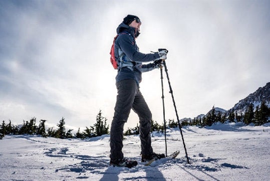 A guest in snowshoes, holding hiking poles