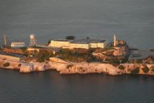 Aerial view of the Alcatraz with the sun shining on it at sunset on the Alcatraz and San Francisco Sites Helicopter Tour.