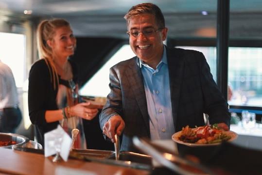 Two guests smiling and plating their food at the buffet on the Baltimore Dinner Cruise in Baltimore, Maryland