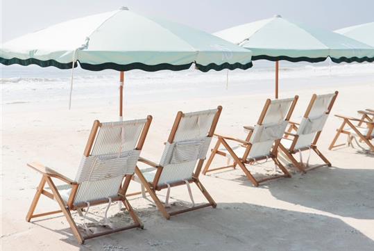 Beach chairs and umbrellas lined up facing the ocean on a sunny day.