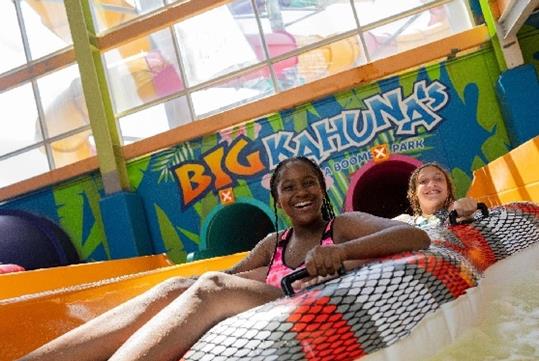Two young girls in tubes on a water slide smiling with a more slides behind them at the Big Kahuna's Water Park.