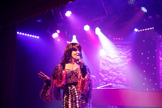 A female singer performing on stage at the Comedy Jamboree show.