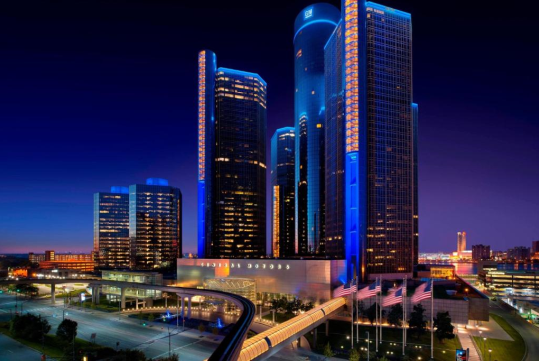 Exterior view of the hotel and Detroit skyline at night.