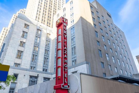 Looking up at the exterior of the Drury Plaza Hotel Pittsburgh Downtown with a red vertical neon sign in front.